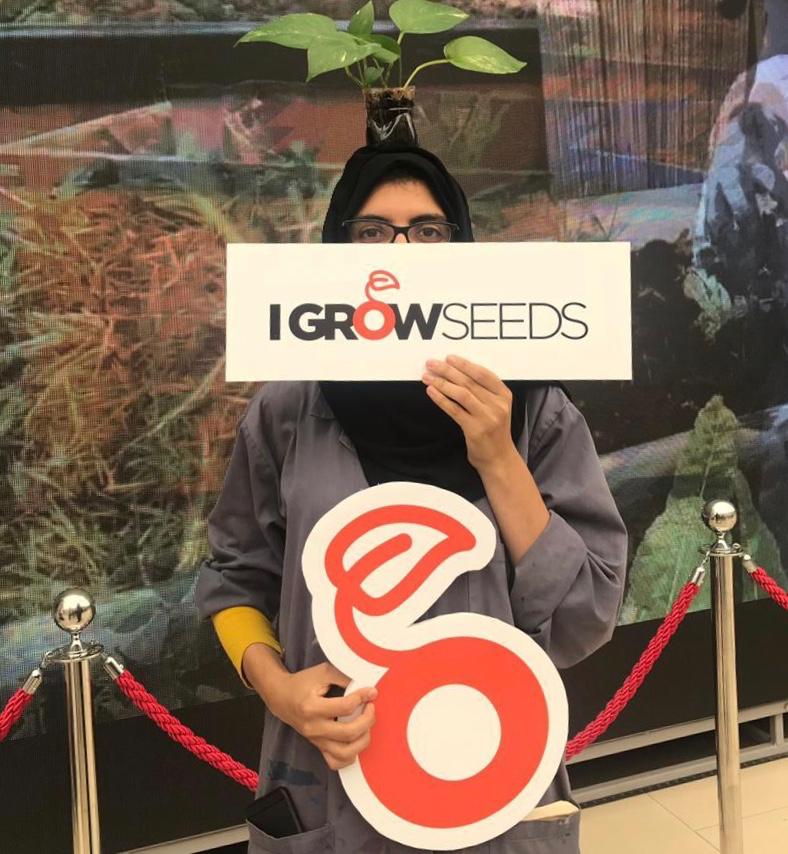 Almanar holding the I GROW SEEDS campaign signs